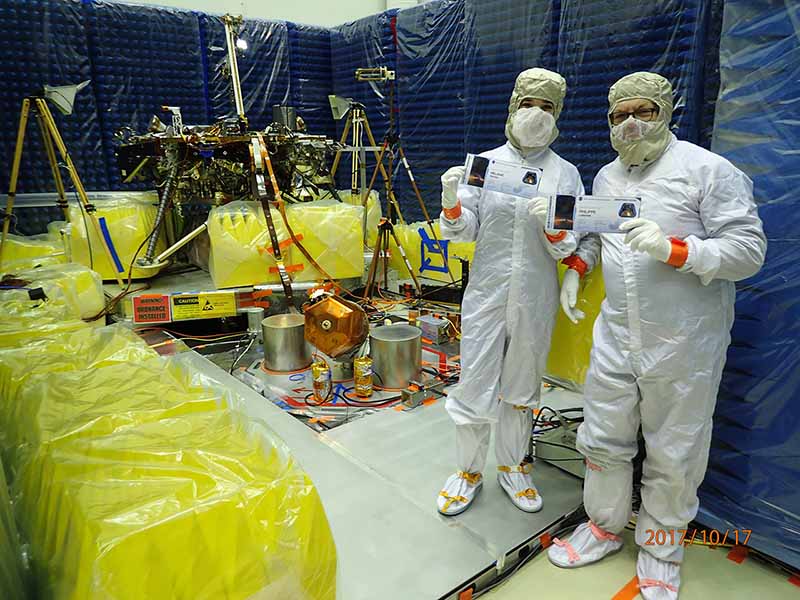 Des membres de l'équipe de planétologie de l'IPGP avec leurs cartes d'embarquement devant la sonde InSight (© Lockheed Martin).